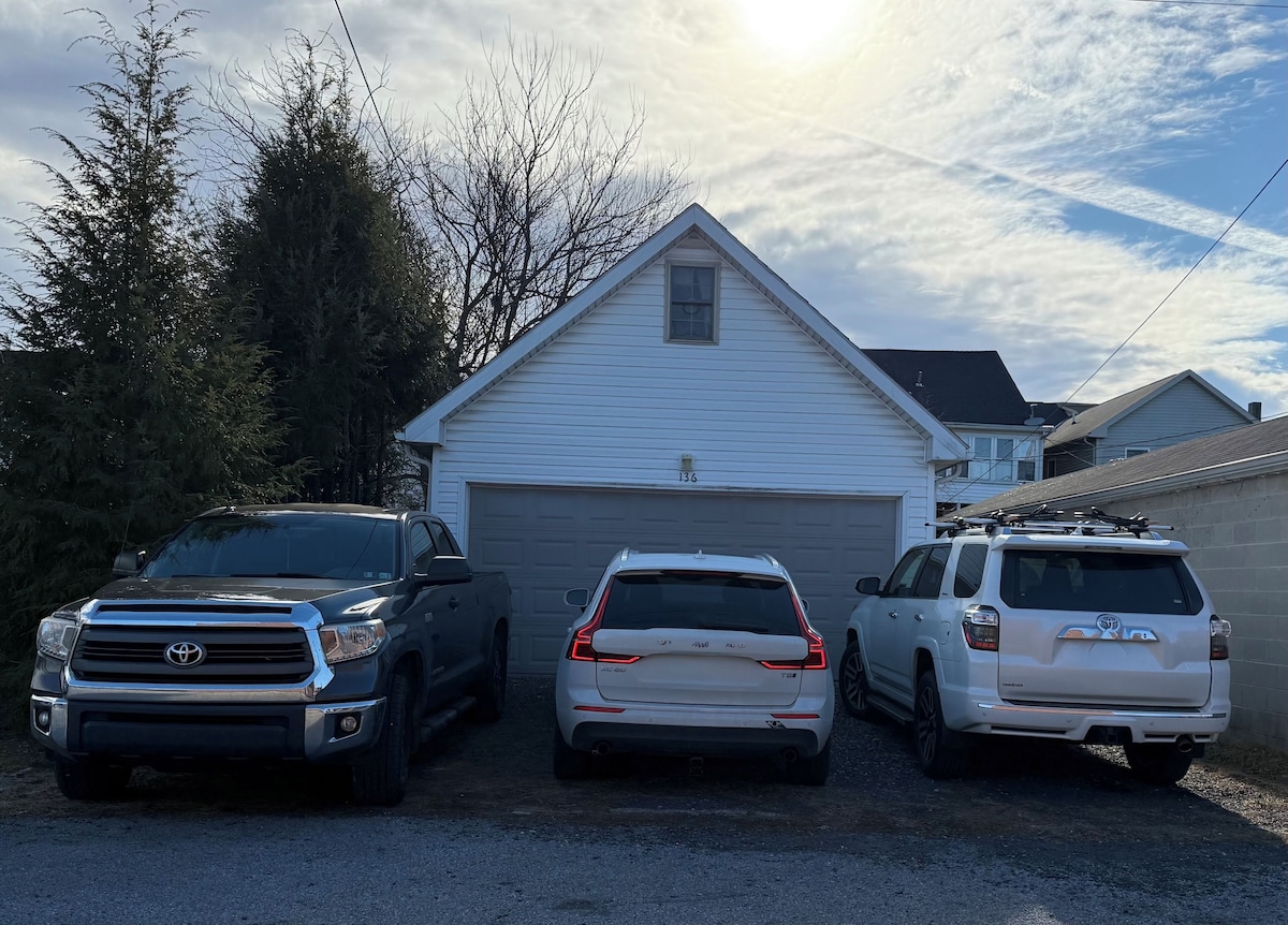 Three vehicles parked in front of a house with a garage.