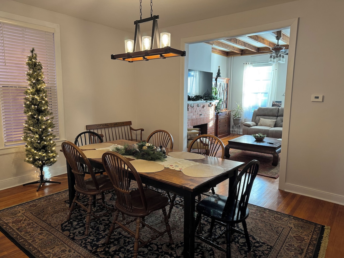 A dining area with a wooden table, chairs, and a Christmas tree.