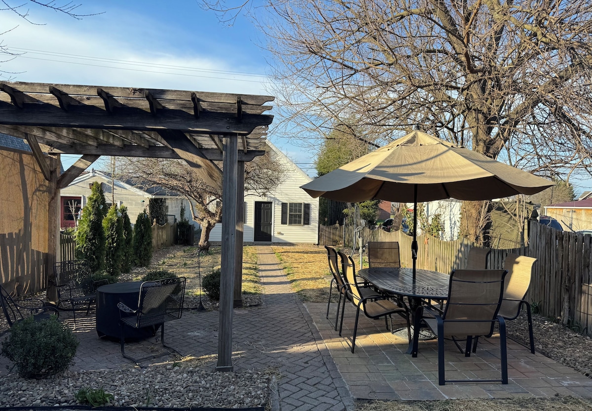 A patio with a pergola, outdoor table and chairs, and a covered umbrella.