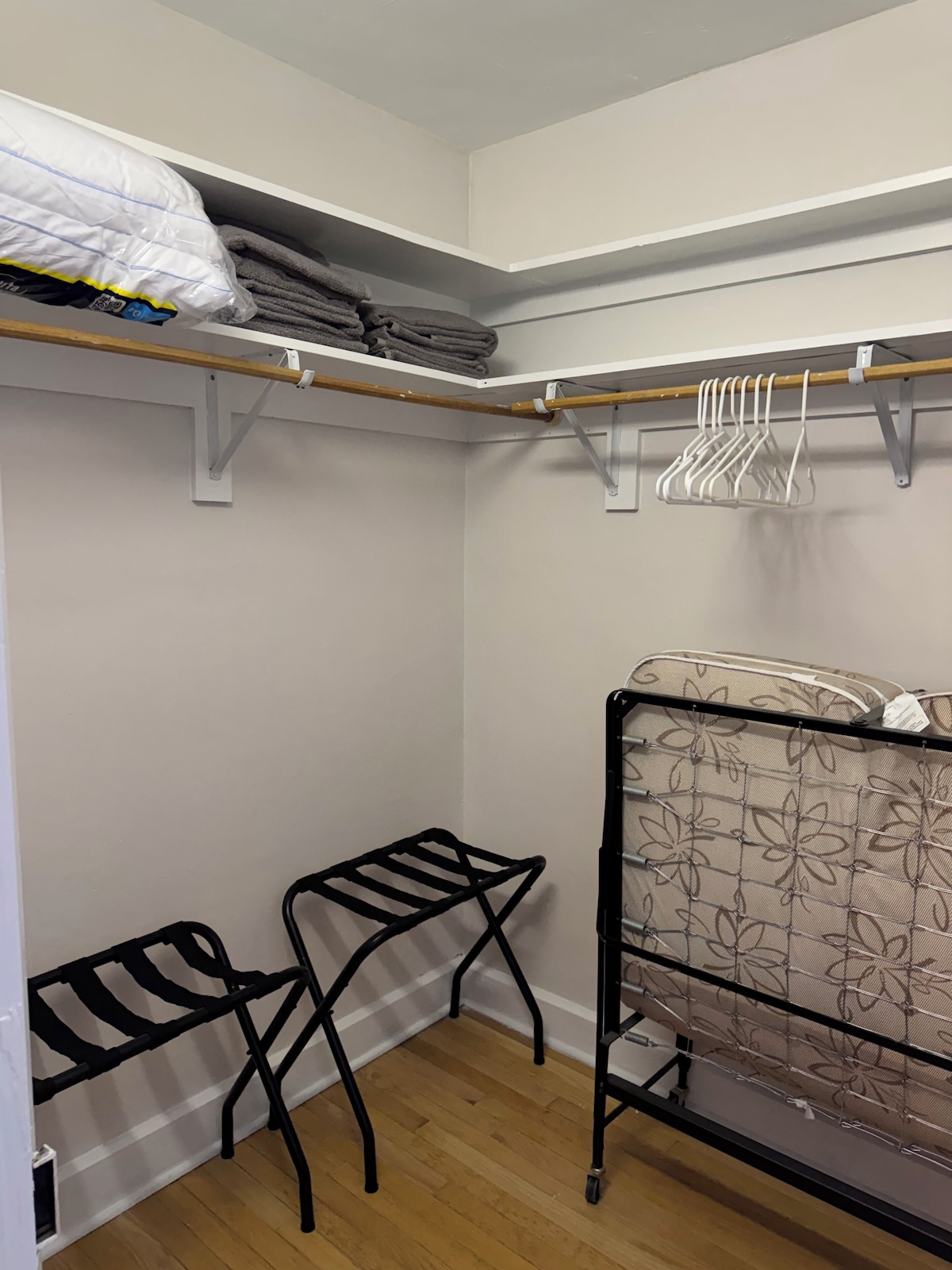 A compact storage closet with shelves, a hanging rack, and a foldable chair.