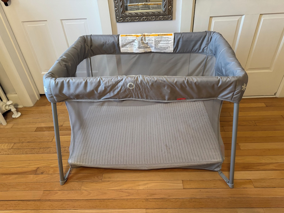 A gray baby stroller with a safety warning label on the seat.