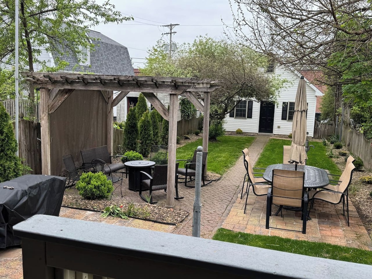 A backyard patio with a pergola, outdoor furniture, and a lawn.