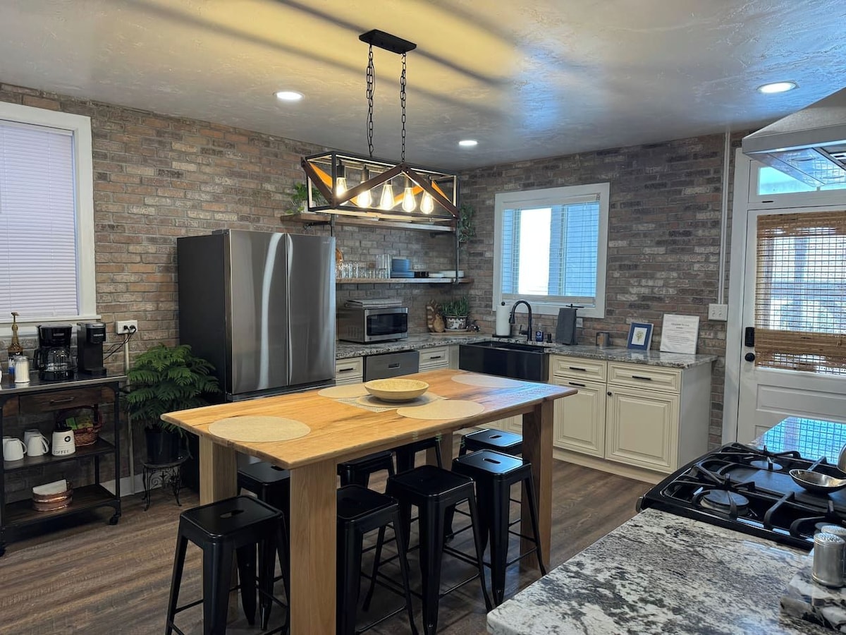A modern kitchen with a central island, stainless steel appliances, and a hanging light fixture.