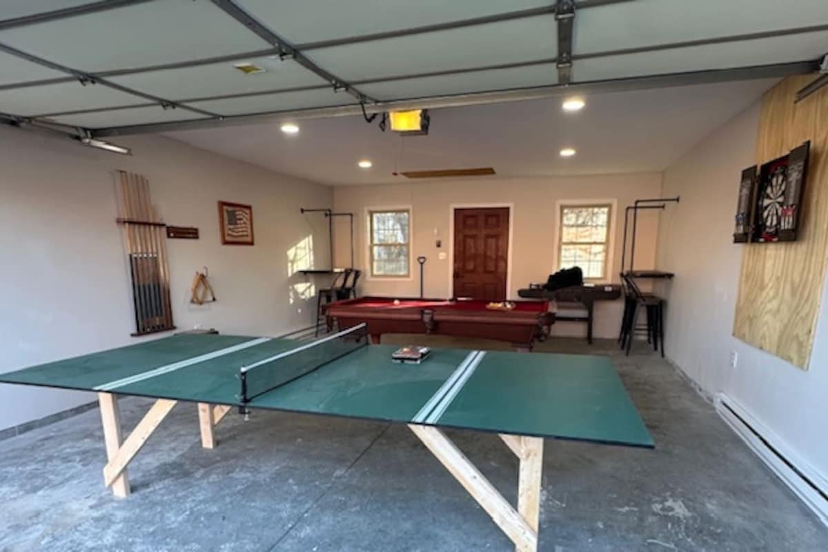 A room with a ping pong table, a pool table, and a billiards table.