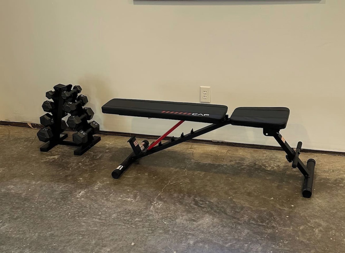 A bench with a weight rack beside it.