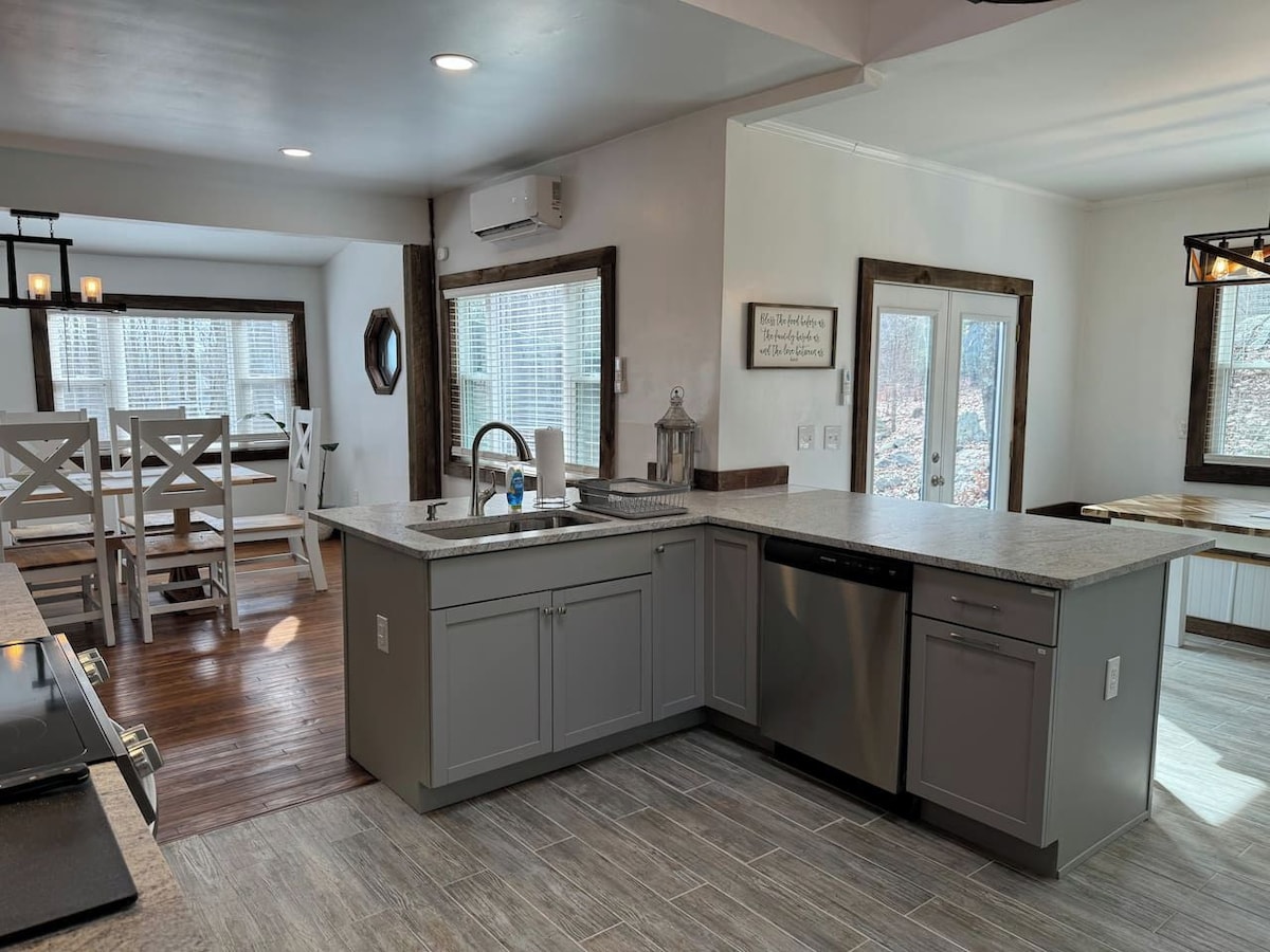 A modern kitchen with a central island, grey cabinetry, and a dishwasher.