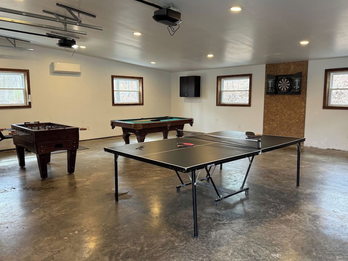 A spacious room with a foosball table, a pool table, and a ping pong table.