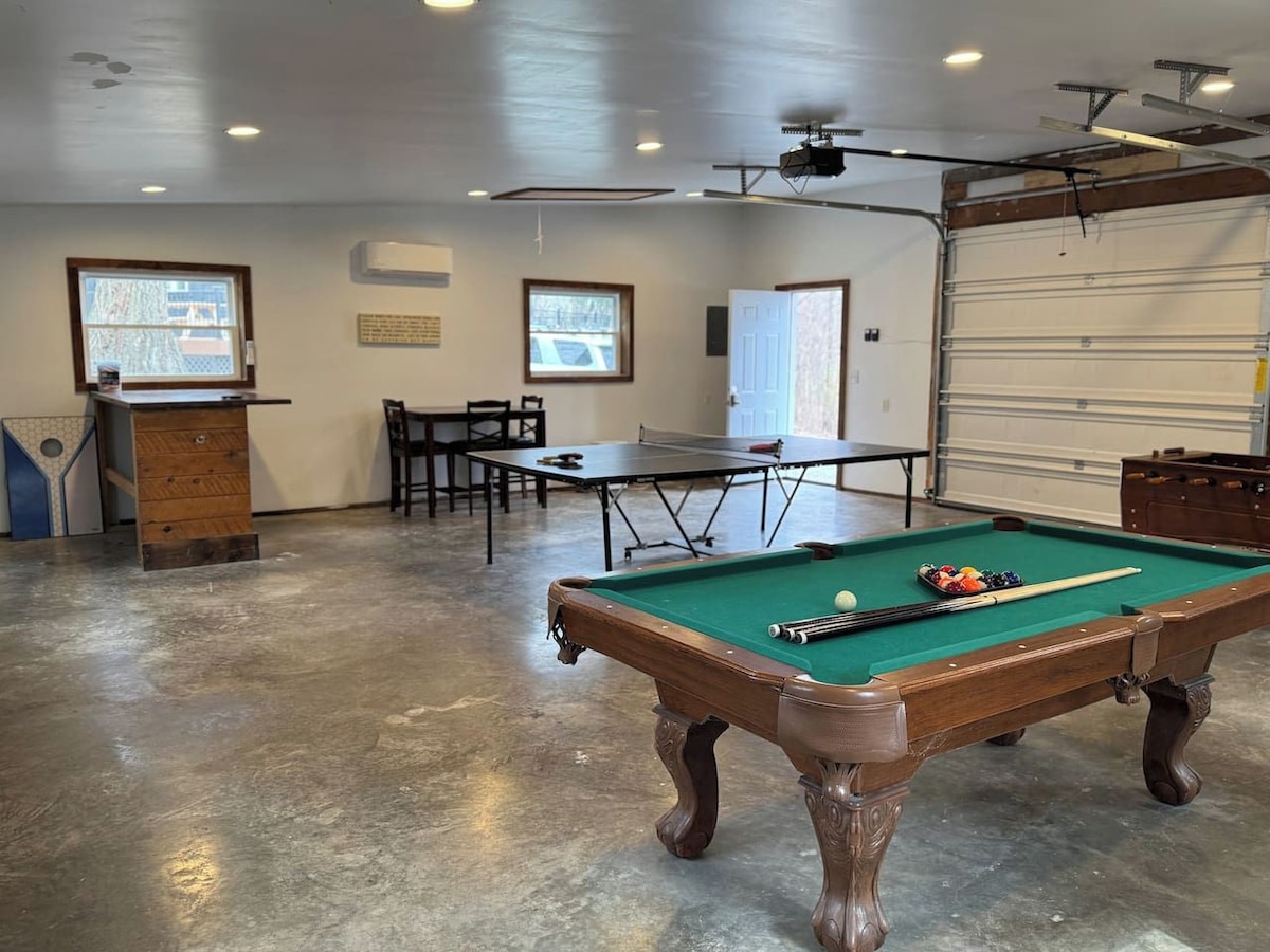 A pool table in a room with a concrete floor, a door, and a garage door.