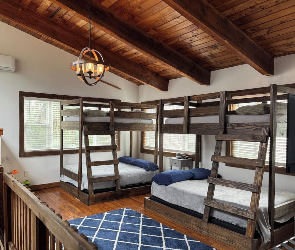 A room with bunk beds, a wooden ceiling, and a hanging light fixture.