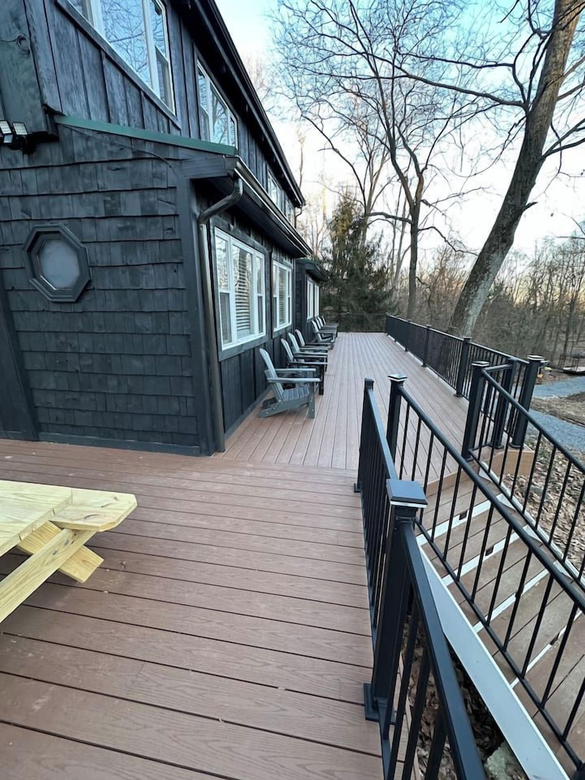 A wooden deck with a black railing, a table, and chairs.